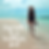 a picture of a woman walking alone on the beach on a sunny clear day.